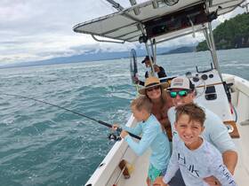 A joyful family enjoys a fishing trip on the ocean, capturing the excitement of their shared experience aboard the boat.