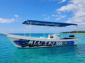A vibrant speedboat named 'All In' glides through crystal-clear waters, showcasing its striking design against a picturesque tropical backdrop.