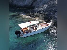 Aerial view of a sleek boat anchored near rocky shores, showcasing its elegant design against the clear turquoise waters.