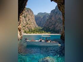 A scenic view of a boat anchored near a stunning beach, with guests enjoying the crystal-clear waters — perfect for snorkeling and relaxation in a picturesque setting.