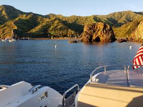 A picturesque view of a tranquil coastline at sunset, showcasing the natural beauty of the landscape with a boat in the foreground — perfect for scenic cruises and island exploration.