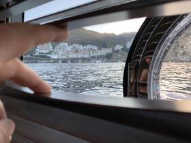 A glimpse from inside the cabin of a boat, showcasing a scenic view of the coastline through a window, perfect for enjoying the serene waterside atmosphere.