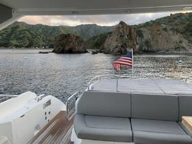 A cozy seating area inside a boat, featuring a view of the serene coastline and rocky formations — perfect for relaxing while enjoying the scenery.