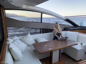 A stylish interior shot of a boat's lounge area featuring a woman working on her laptop, showcasing the perfect blend of comfort and functionality on the water.