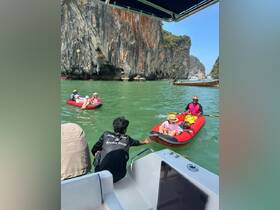 A family enjoys kayaking in a stunning natural setting, with towering cliffs and clear waters providing the perfect backdrop for an adventurous day on the water.
