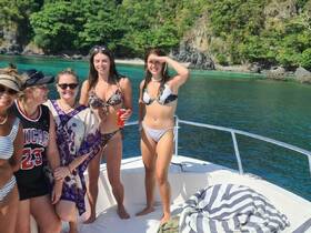 A fun group of friends enjoys a sunny day on a boat, showcasing their vibrant swimsuits and the beautiful turquoise waters — perfect for a memorable summer getaway.