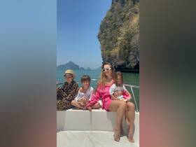 A joyful family enjoys a sunny day on a boat, surrounded by stunning coastal scenery — perfect for memorable family outings on the water.
