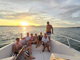 A cheerful group of friends enjoys a sunset cruise on a boat, capturing the perfect moment of camaraderie and relaxation on the water.