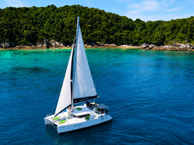A stunning aerial view of a catamaran sailing through crystal-clear turquoise waters, surrounded by lush greenery — perfect for island hopping adventures.