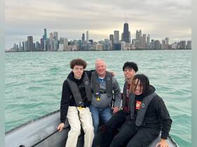 A group of four enjoys a boating adventure on Lake Michigan with the stunning Chicago skyline in the background, perfect for family outings and city tours.