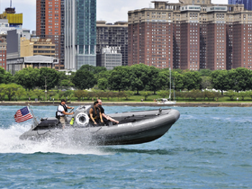 A speedboat navigates through the water with passengers enjoying the ride, set against a vibrant city skyline — perfect for urban boating adventures.