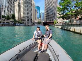 A couple enjoys a scenic boat ride through the vibrant cityscape, surrounded by towering skyscrapers and sparkling waters — perfect for urban exploration.