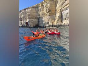 A lively group enjoys kayaking near stunning cliffs, showcasing the thrill of adventure on the water.