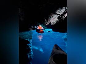 A kayaker navigates through a stunning cave, surrounded by vibrant blue waters — an exhilarating adventure perfect for exploration enthusiasts.