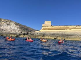 A group of kayakers paddles along a stunning coastline, enjoying the beautiful scenery and clear blue waters — perfect for adventure seekers and nature lovers.