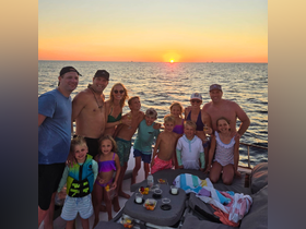 A joyful family gathers on a boat at sunset, celebrating with drinks and snacks — a perfect moment for cherished memories on the water.