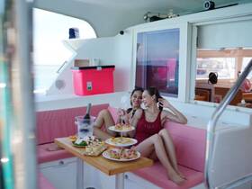 Two friends enjoy a delightful spread of food and drinks in the cozy interior of a boat, perfect for a relaxing day on the water.