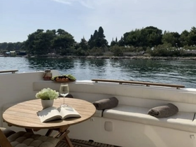 A cozy interior setting on a boat featuring a wooden table with a glass of wine, an open book, and a platter of snacks, perfect for relaxing moments on the water.