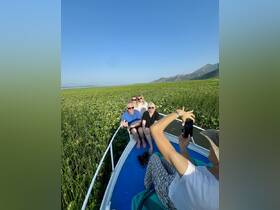 A cheerful group poses for a photo on a boat surrounded by lush water lilies, capturing a memorable moment in nature.