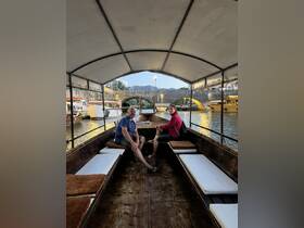 A cozy interior view of a boat featuring two guests seated comfortably, showcasing the inviting atmosphere perfect for leisurely rides along scenic waterways.