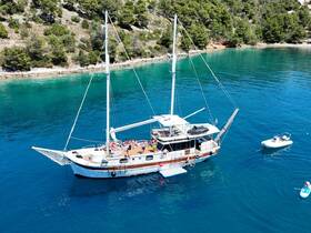 A lively group enjoys a day on a beautiful sailing boat in turquoise waters, perfect for island hopping adventures and summer fun.