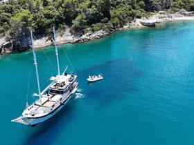 A stunning aerial view of a luxurious yacht cruising through crystal-clear waters, surrounded by lush greenery — perfect for exploring secluded beaches and enjoying the beauty of nature.
