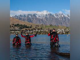 A group of divers stands in the water, ready for an adventure against a stunning mountain backdrop — perfect for thrill-seekers and nature lovers.