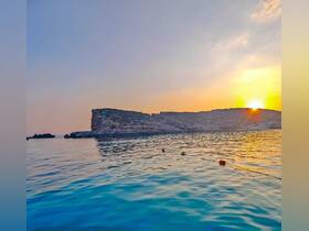 A stunning sunset over a tranquil coastline, reflecting on calm waters — a perfect backdrop for evening boat trips and scenic cruises.
