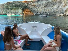 A cozy interior view of a boat with guests seated, enjoying the scenic surroundings of a coastal cave. Perfect for relaxing during a boat tour.