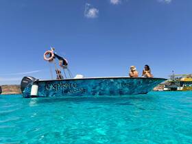 A couple enjoys a sunny day on a vibrant boat in the crystal-clear waters of Gozo, perfect for exploring the beautiful coastline.
