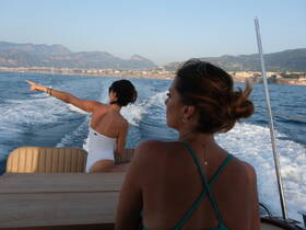 Two friends enjoy a scenic boat ride, with one pointing out the beautiful coastline — a perfect moment for adventure and exploration on the water.