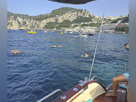Guests enjoy a refreshing swim in the beautiful waters off Capri, surrounded by stunning coastal scenery — a perfect day for relaxation and fun on the water.