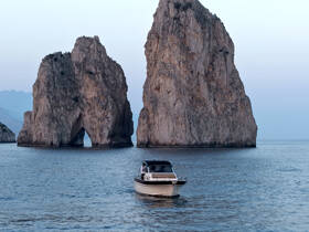 A scenic view of a boat navigating near stunning rock formations, showcasing the beauty of coastal landscapes.