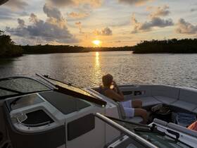 A serene sunset view from a boat with a guest enjoying the moment, perfect for capturing the tranquility of a day on the water.