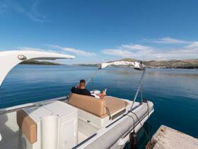 A man relaxes on the deck of a boat, enjoying the serene waters and picturesque landscape — a perfect setting for a tranquil day on the water.