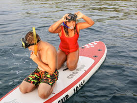 Two kids enjoy snorkeling on a paddleboard, showcasing the fun of water activities and adventure in the sun.