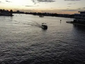 A scenic view of a speedboat cruising through calm waters at sunset, showcasing the tranquil beauty of the waterfront.