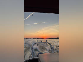A stunning sunset view from the back of a boat, showcasing the tranquil waters and a beautiful sky, perfect for evening cruises.
