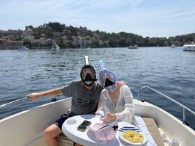 A couple prepares for a snorkeling adventure on their boat, enjoying snacks and the beautiful scenery — perfect for a fun day on the water.