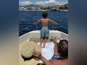 A child enjoys the view from the bow of a boat while family members relax nearby, capturing a perfect moment of joy and togetherness on the water.