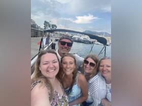 A cheerful group of friends poses for a selfie on a boat, capturing a joyful moment on the water — perfect for memorable outings and celebrations.