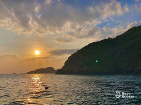 A serene sunset view with a swimmer in the foreground, capturing the tranquil beauty of the coastline — perfect for sunset cruises and relaxing moments on the water.