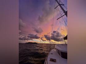 A stunning sunset view from the deck of a yacht, showcasing vibrant colors in the sky and a distant island, perfect for capturing the essence of serene sailing experiences.