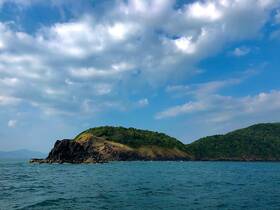A stunning view of a lush green island with rocky outcrops, set against a vibrant blue sky — perfect for showcasing the natural beauty of coastal destinations.