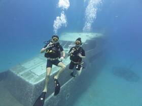 Two divers explore an underwater wreck, showcasing the thrill of scuba diving and marine adventure in crystal-clear waters.