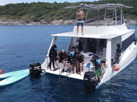 A lively group prepares for a diving adventure aboard a boat, with paddleboards at the ready — perfect for exploring underwater wonders.