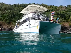 A scenic view of a boat with people fishing off the side, set against a lush green backdrop in Thailand — perfect for adventure seekers and fishing enthusiasts.