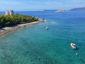 A stunning view of boats anchored near a picturesque island, with people enjoying the clear waters — a perfect setting for a day of relaxation and exploration.