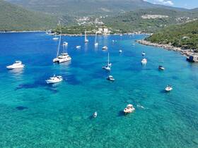 A stunning aerial view of a vibrant bay filled with various boats, showcasing a swimmer enjoying the crystal-clear waters — perfect for island hopping and aquatic adventures.