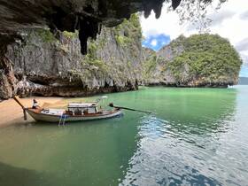 A scenic view of a traditional boat anchored near a secluded beach, with lush cliffs in the background — perfect for fishing and exploring hidden gems.